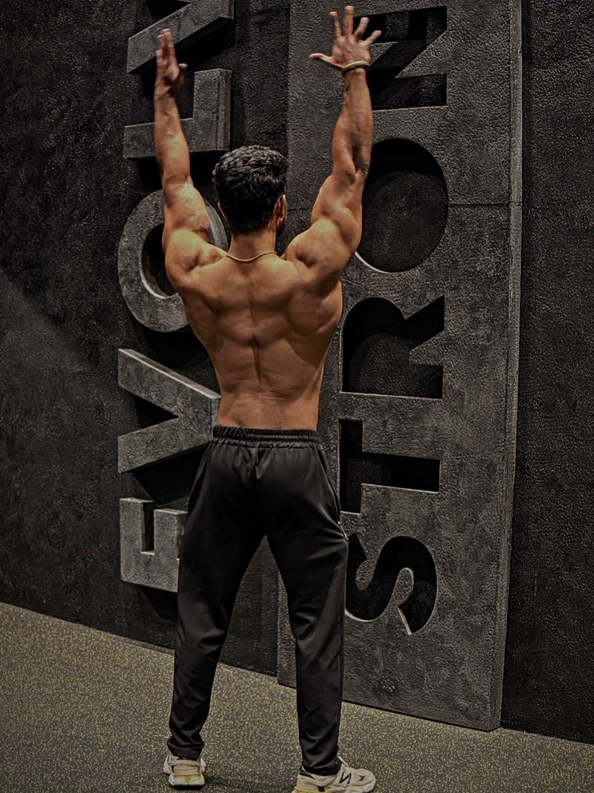 B6 athlete back lat-spread pose against the EVOLVE STRONG wall